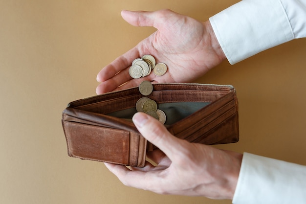 Münzen in der Hand und in einer leeren Brieftasche