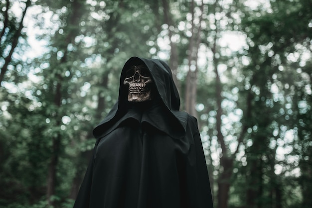 Muerte en sudadera con capucha negra en el bosque