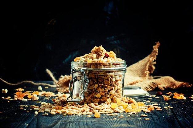 Muesli al horno con pasas y semillas de girasol en un frasco de vidrio enfoque selectivo de fondo negro