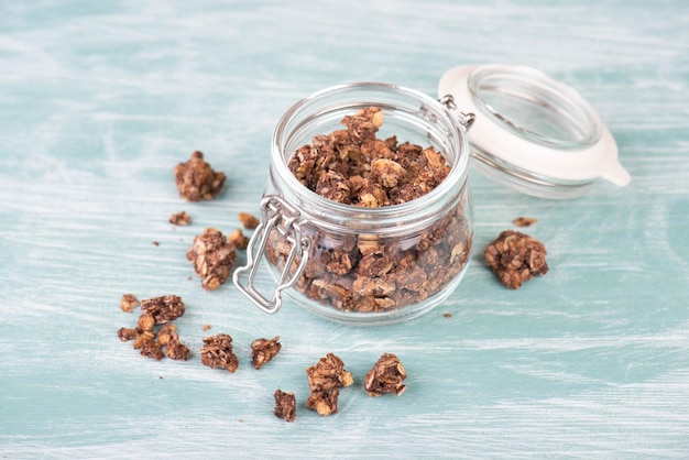 Muesli con chocolate en un vaso sobre un fondo azul turquesa y blanco en mal estado, espacio vacío