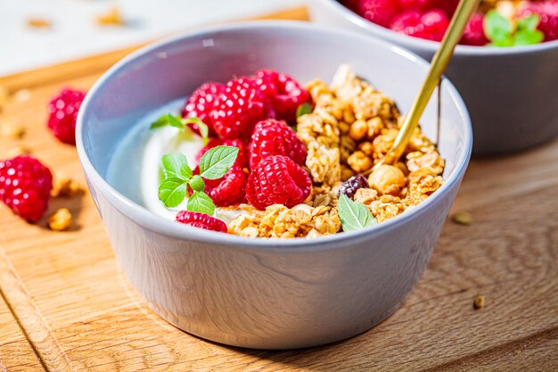 Muesli com framboesas e iogurte em uma tigela cinza.