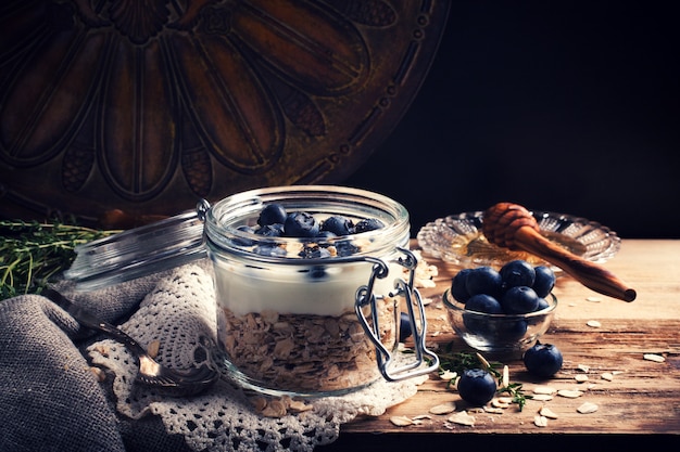 Foto muesli com iogurte e frutas azuis em frasco de vidro.