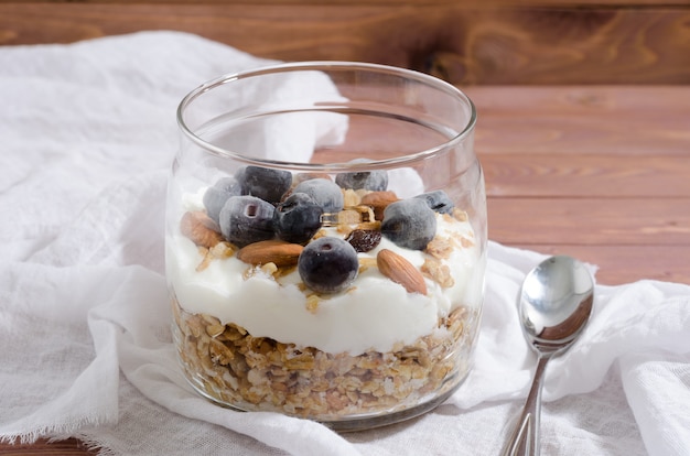 Muesli com iogurte natural, mirtilo, nozes e frutas secas em uma jarra de vidro