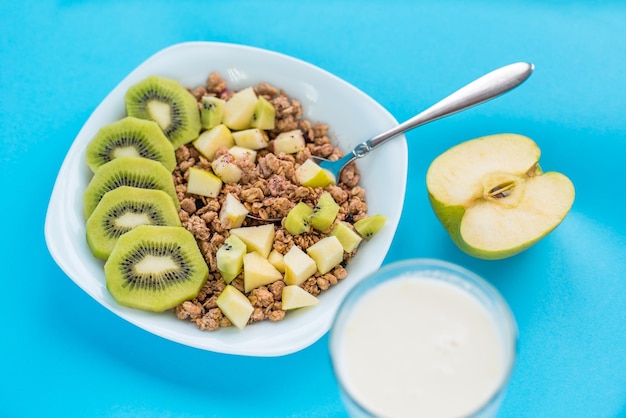 Muesli com kiwi e maçã com leite em um fundo azul