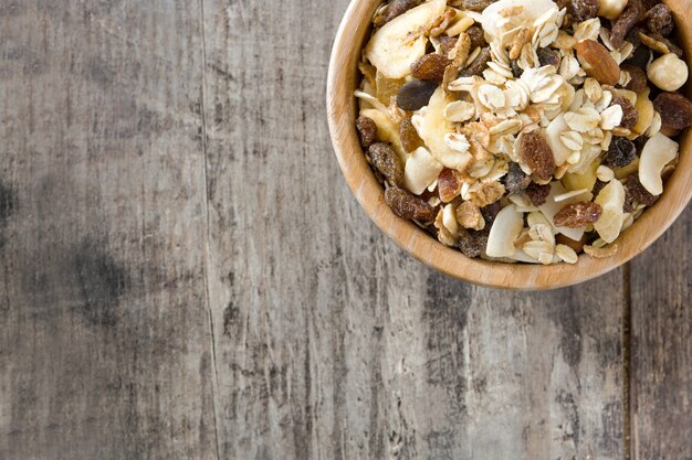 Muesli e frutos secos em uma tigela de madeira na mesa de madeira.