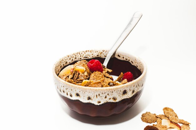 Muesli con frambuesas y leche en un tazón sobre un fondo blanco Desayunos saludables nutrición adecuada