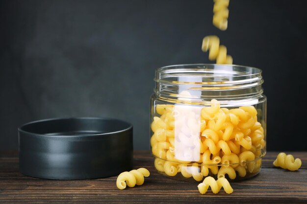 Müsli in der Küche aufbewahren Nudeln in einem transparenten Behälter auf dunklem Hintergrund in Nahaufnahme