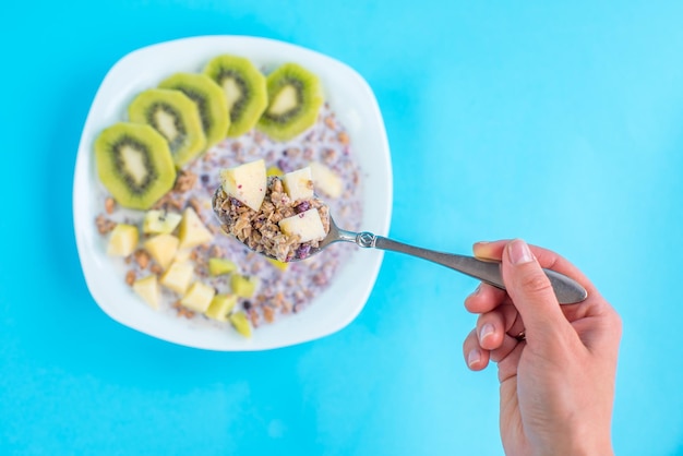 Muesli con kiwi y manzana con leche sobre un fondo azul.