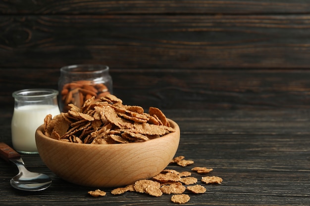 Muesli, leche, almendras y cuchara de mesa de madera