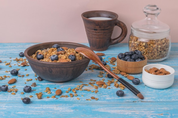 Muesli con leche y yogur sobre una mesa azul sobre un fondo rosa.