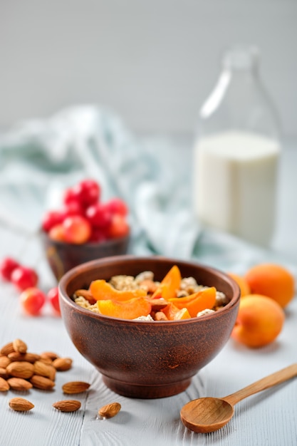 Müsli mit Aprikosen und Mandeln auf weißem Holztisch