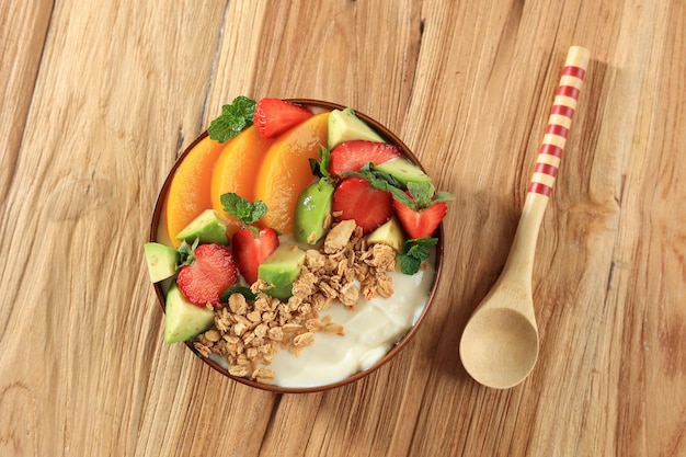 Müsli mit griechischem Joghurt, Pfirsich, Avocado und Erdbeere in der Schüssel