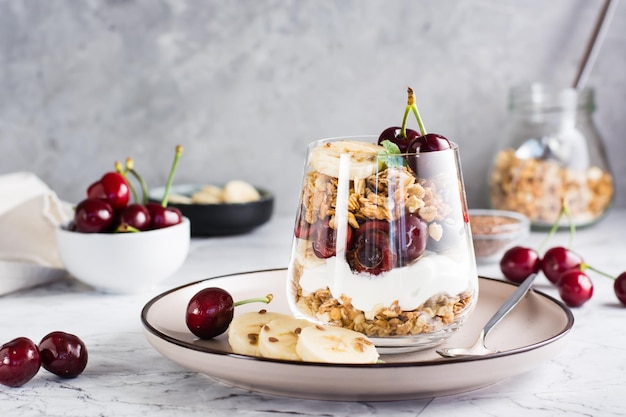 Müsli mit griechischer Joghurtkirsche und Banane in einem Glas auf dem Tisch Hausgemachtes gesundes Frühstück