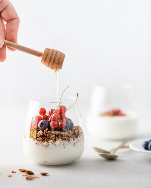 Müsli mit Joghurt, Beeren und Honig in einem Glas