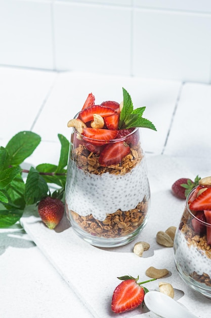 Müsli mit Joghurt-Chia und Erdbeeren in einem Glas auf weißem Hintergrund