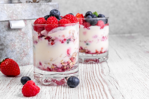 Müsli mit Joghurt und Beeren im Glas auf weißem Hintergrund