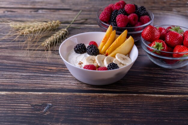 Müsli mit Joghurt und Obst auf einem dunklen Holztisch