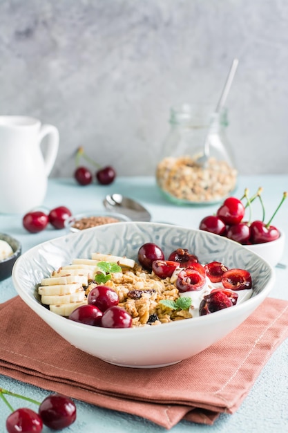 Müsli mit Kirschbanane und Leinsamen in einer Schüssel und ein Glas Müsli auf dem Tisch Vertikale Ansicht