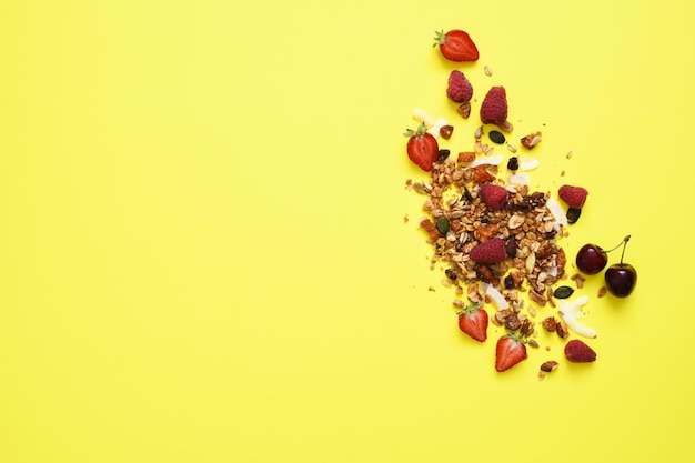 Müsli mit Nüssen und Beeren auf gelbem Hintergrund Ansicht von oben