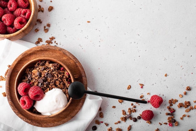 Müsli mit Schokolade, Nüssen und frischen Himbeeren in Holzschalen, Draufsicht