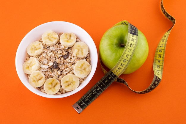 Muesli con plátano en un plato blanco sobre una naranja