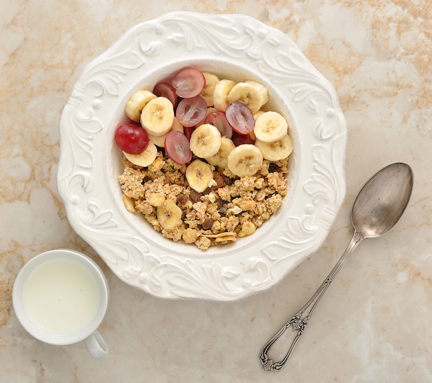 Foto muesli con plátano, uvas y leche. desayuno saludable.