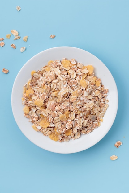 Muesli en un plato blanco sobre un fondo azul.