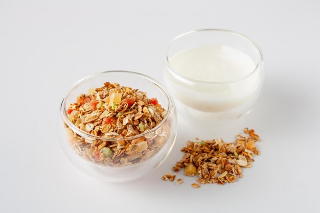 Müsli und Glas mit Joghurt auf weißem Hintergrund