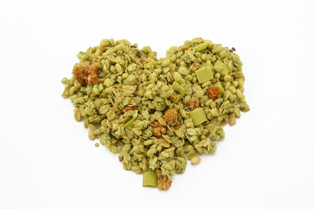 Muesli vegano verde en forma de corazón aislado sobre fondo blanco.