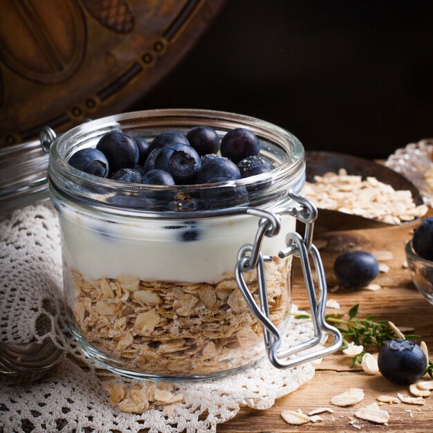Muesli con yogur y bayas azules en frasco de vidrio.