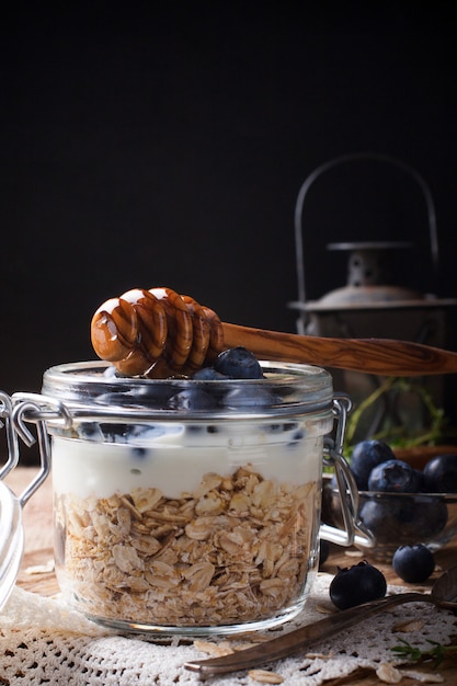 Muesli con yogur y bayas azules en frasco de vidrio.