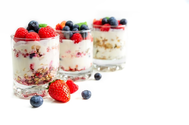 Muesli con yogur y bayas en un vaso sobre un fondo blanco.