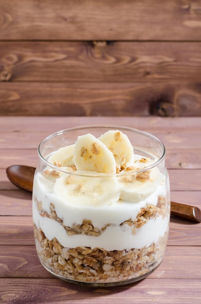 Muesli con yogur natural, plátano, nueces y frutas secas en un frasco de vidrio