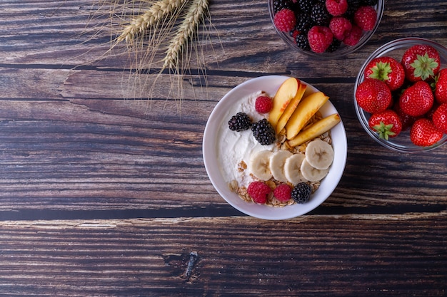 Muesli con yogurt y fruta sobre una mesa de madera oscura.