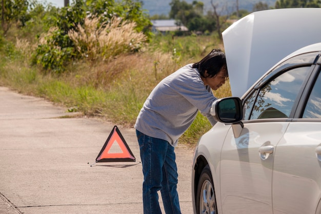 Muestra y conductor de parada de emergencia cerca del coche roto en el camino.