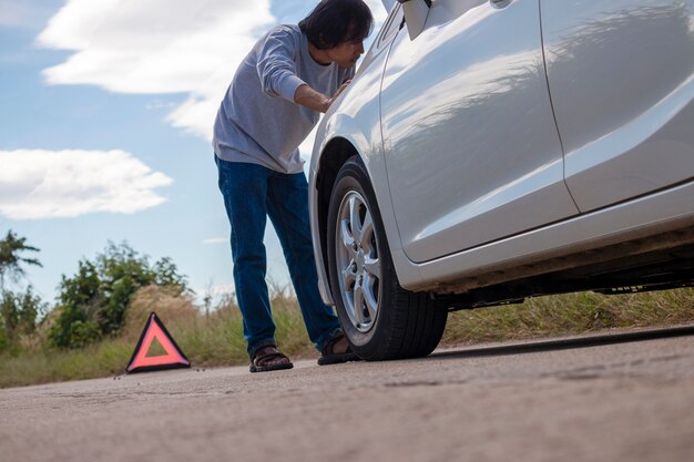 Foto muestra y conductor de parada de emergencia cerca del coche roto en el camino.