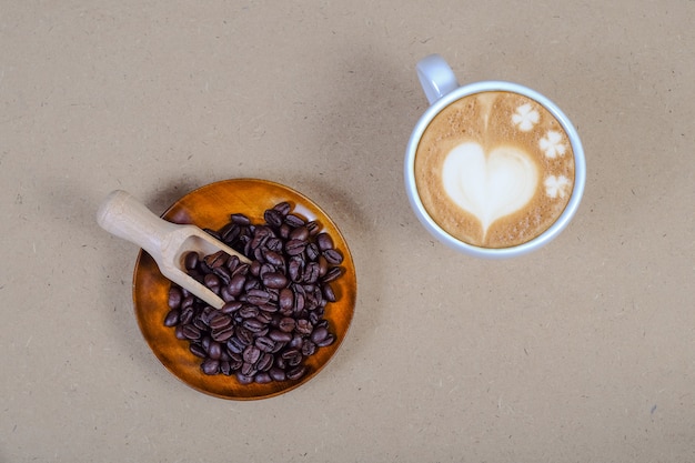 Muestra del corazón en café del arte tardío con el grano de café fresco en la tabla.