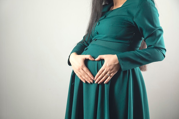 Muestra del corazón de la mano de la mujer embarazada en el vientre