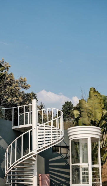 Se muestra una escalera frente a una casa con un cielo azul de fondo.