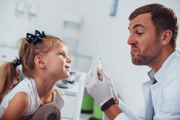 Muestra de sangre. La niña con su osito de peluche está en la clínica con el médico.