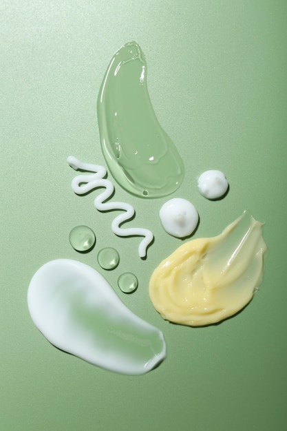 Muestras de crema y gel en fondo verde vista de arriba