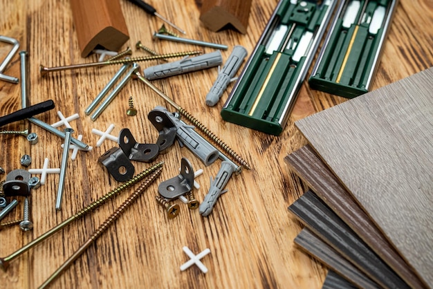 Muestras de madera de accesorios de muebles junto a tornillos y una llave en una mesa de madera