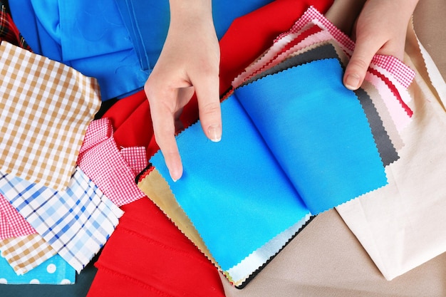 Muestras de telas coloridas en manos femeninas sobre fondo de mesa de madera