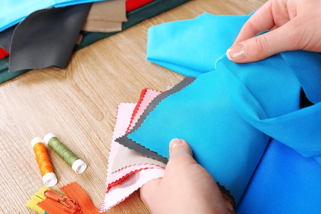 Muestras de telas coloridas en manos femeninas sobre fondo de mesa de madera