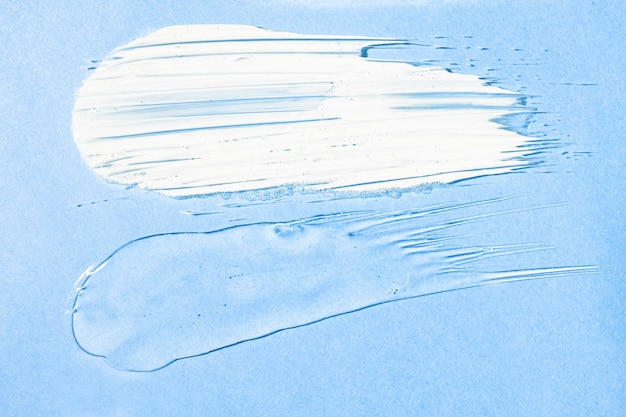 Muestras de textura de gel transparente y crema en una vista superior de fondo azul