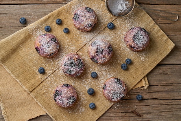 Muffin de arándanos, vista superior. Magdalenas con bayas en servilleta de lino rústico viejo, mesa de madera