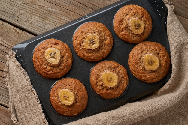 Muffin De Banana En Bandeja, Vista Superior. Magdalenas en servilleta de lino antiguo, mesa de madera rústica