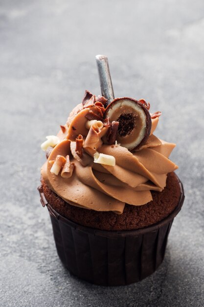 Muffin de chocolate con crema decorado con dulces y chispas de chocolate.