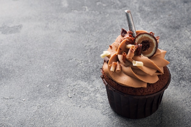 Muffin de chocolate con crema decorado con dulces y chispas de chocolate