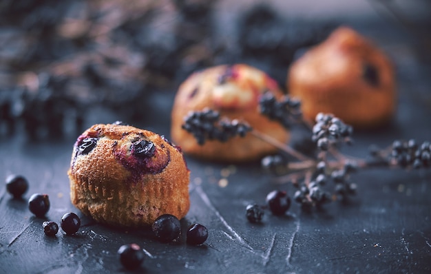 Muffin com groselha em um fundo escuro ao lado das bagas nos ramos. em estilo rústico. estilo escuro